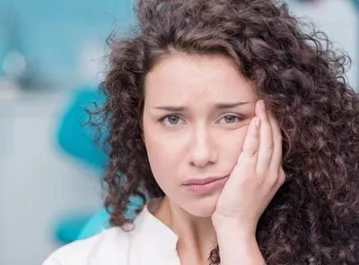 woman holding her mouth from tooth pain in need of an emergency dentist