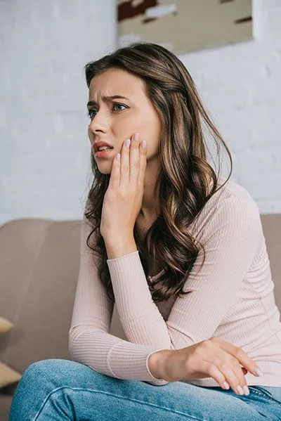 woman sitting in the waiting room holding her mouth due to tooth pain
