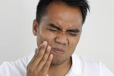 man holding his mouth due to tooth pain