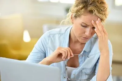 woman taking a break from looking at her laptop due to a migraine
