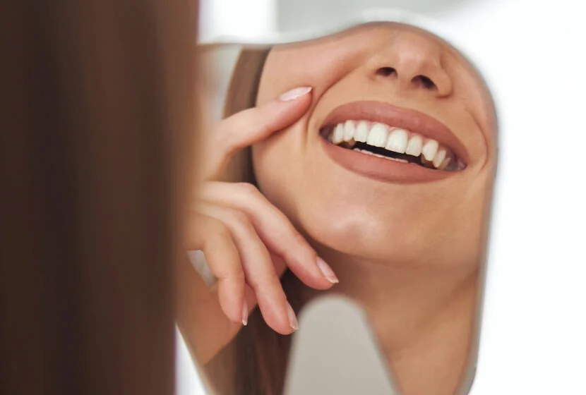 woman smiling in the mirror after visiting Jonesboro dental office Southard Family Dentistry