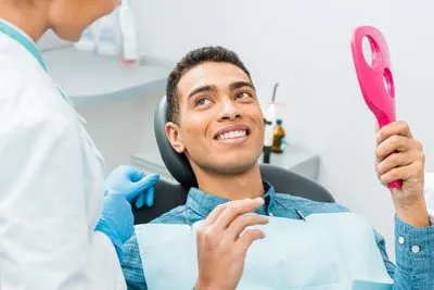 patient looking in the mirror satisfied with the results of his restorative dentistry procedure given by Southard Family Dentistry