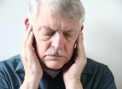man experiencing symptoms of TMJ holding his jaw